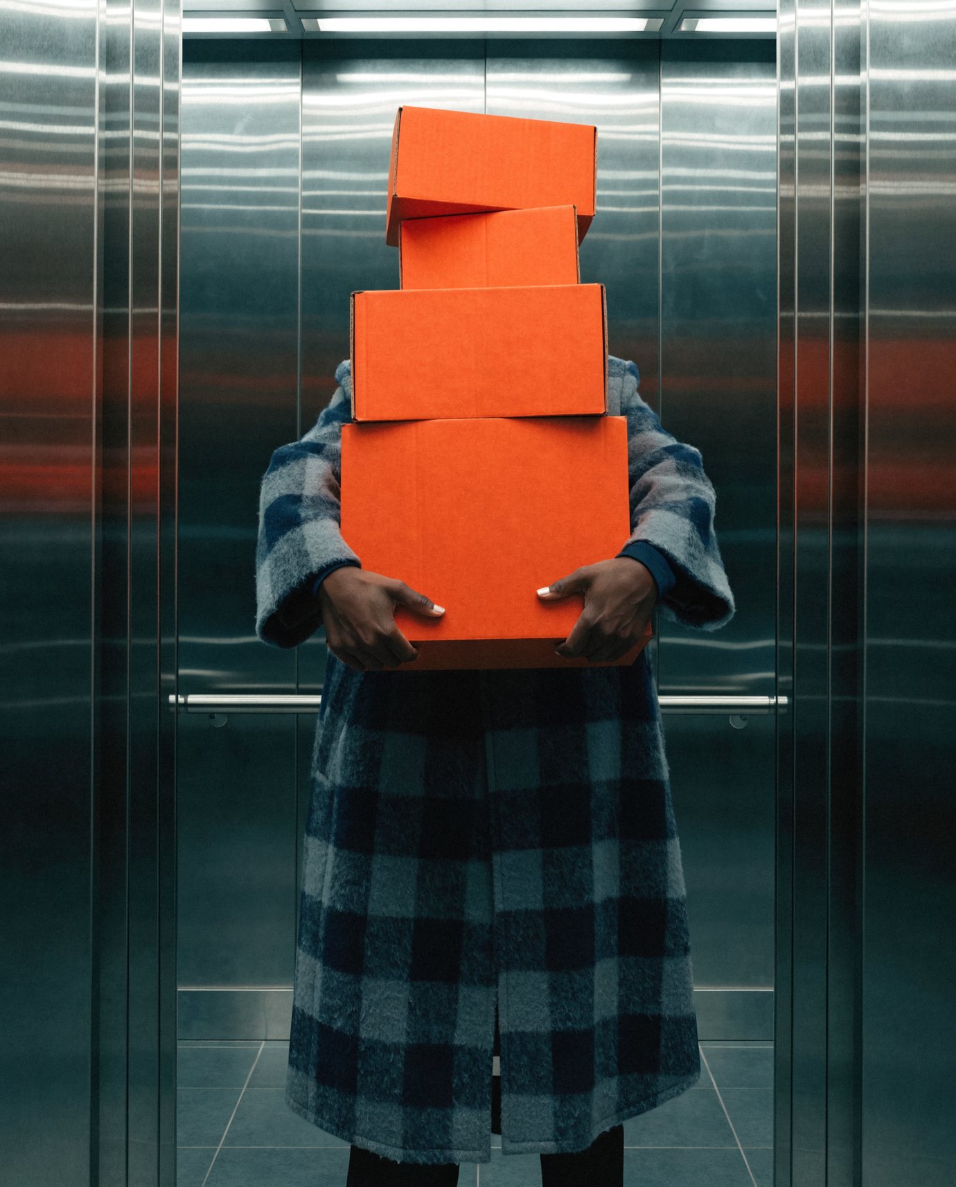A delivery carried in, a stack of orange boxes in both arms